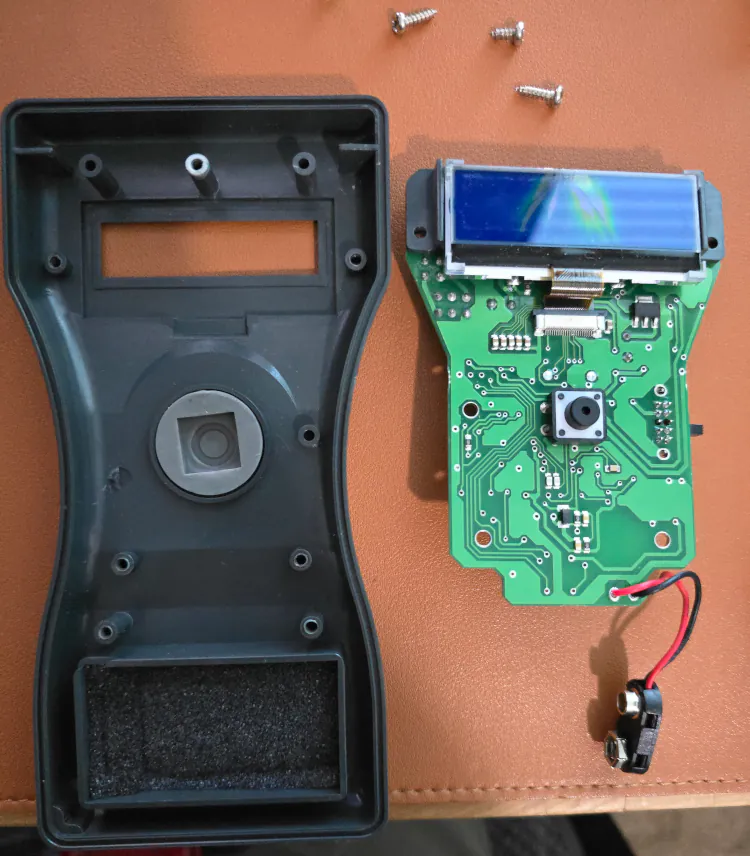 the inside of the top half of the enclosure, alongside the other side of the PCB with broken display.